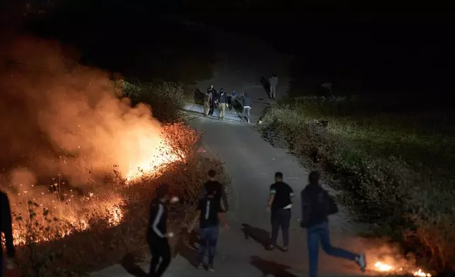 以色列定居者（上方）與巴勒斯坦人爆發衝突，路邊灌木叢燃燒，此前巴勒斯坦人點燃灌木叢以阻止定居者接近約旦河西岸辛吉爾村莊。2026年7月17日周五。(美聯社圖片/Leo Correa) AP圖片