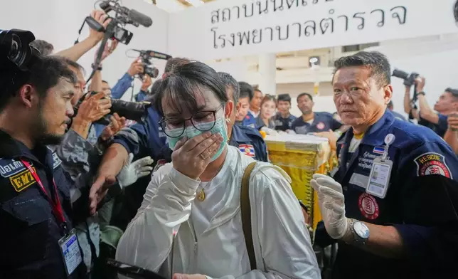 2026年7月14日周二，泰國曼谷一間警務醫院，一名音樂酒吧火災遇難者家屬引導載有遇難者遺體的棺木移送上車。(美聯社圖片/Sakchai Lalit) AP圖片