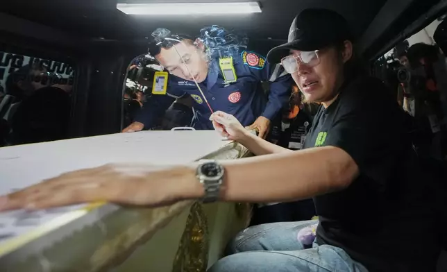 曼谷一間音樂酒吧火災的遇難者家屬，坐在載有遇難者遺體的車輛旁，遺體正從警方法醫醫院轉移。攝於2026年7月14日周二。(美聯社圖片/Sakchai Lalit) AP圖片