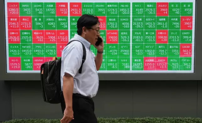 一名男子周二（2026年6月23日）走過東京證券交易所顯示公司股價的屏幕。 (美聯社圖片/Hiro Komae) AP圖片
