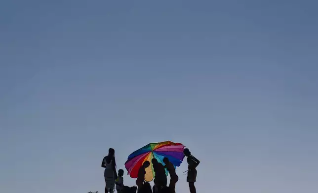 2026年7月29日周三，加州亨廷頓海灘，泳客在風中努力固定太陽傘。(美聯社圖片/Jae C. Hong) AP圖片