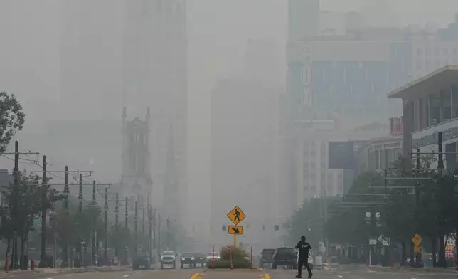 周四（2026年7月16日），底特律，一名行人過馬路，底特律城市天際線在加拿大山火煙霧導致空氣質素惡劣期間被遮蔽。(美聯社圖片/Paul Sancya) AP圖片