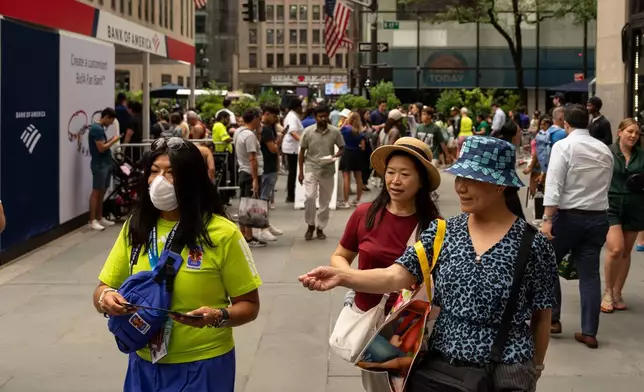 一名世界盃義工戴著口罩，山火濃煙籠罩紐約洛克菲勒中心球迷村的天空。攝於2026年7月16日周四。(美聯社圖片/Yuki Iwamura) AP圖片