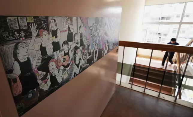 (美聯社圖片/Hiro Komae) 二零二六年七月二十一日周二，在東京西北部熊谷的熊谷女子高等學校，一名教師走下樓梯，旁邊是走廊上展示的黑板藝術作品。該校藝術學會成員曾於二零二三年贏得全國黑板藝術比賽首獎。 AP圖片