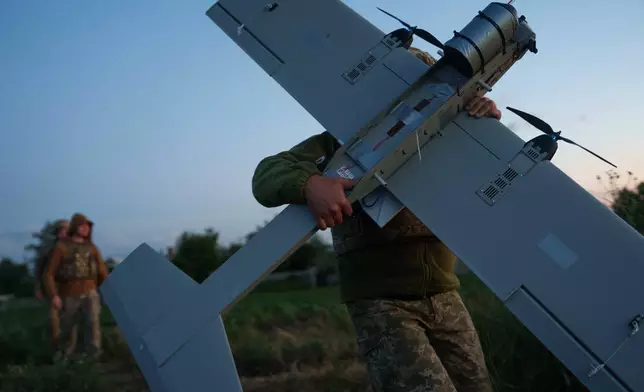 烏克蘭無人系統部隊K-2旅一名軍人，2026年6月22日周一在烏克蘭頓涅茨克地區前線的起飛位置，攜帶一架中程無人機，準備飛往俄軍陣地。(美聯社圖片/Evgeniy Maloletka) AP圖片