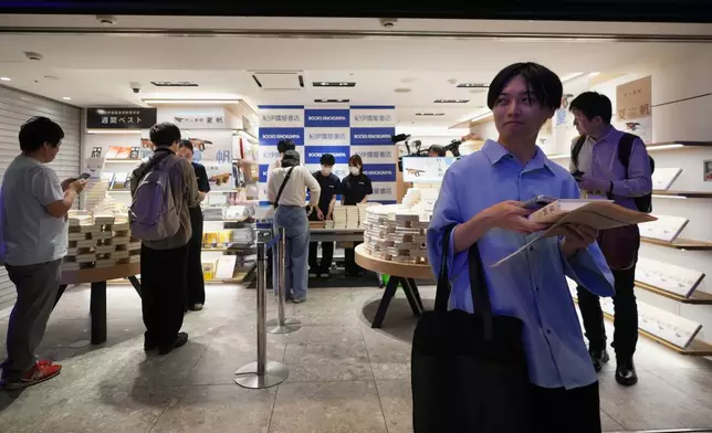 2026年7月3日周五午夜時分過後數分鐘，一名男子在東京紀伊國屋書店的倒數活動中領取村上春樹新書《加穗的故事》，其他人則在排隊等候。 (美聯社圖片/Hiro Komae) AP圖片