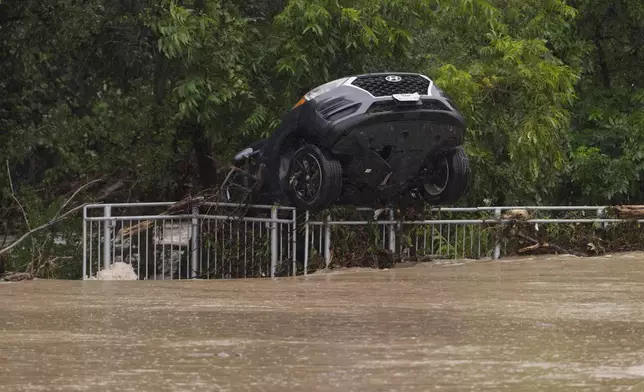 一輛被洪水損毀的汽車周三（2026年7月15日）在德州伯爾尼，掛在圍欄上。(美聯社圖片/Darren Abate) AP圖片