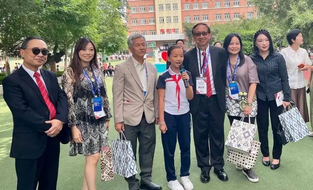 代表團成員參觀新疆師範大學附屬中學（田家炳中學）並與熱情講解的優秀學生合影