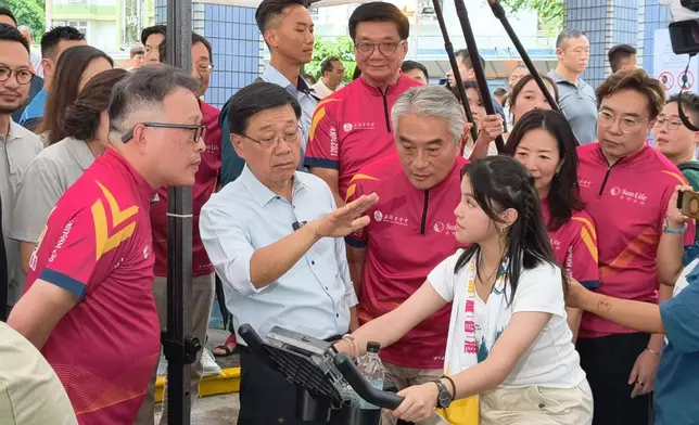 元州邨平台正有機構舉辦社區活動，現場放置智能健身單車，李家超與參加者傾談。巴士的報記者攝