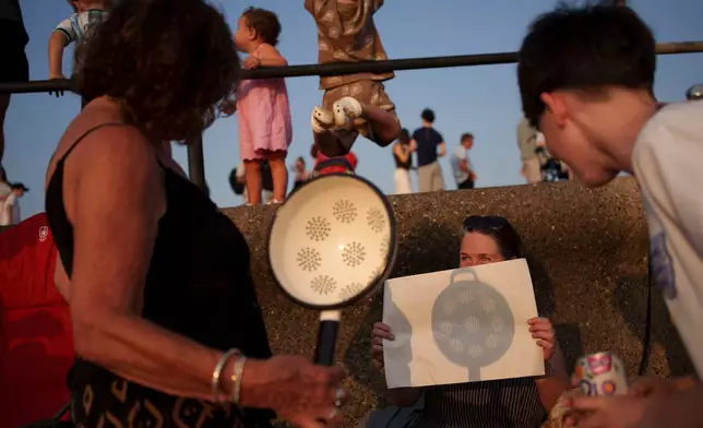 2026年8月12日周三，在英格蘭利物浦附近的克羅斯比海灘，民眾使用濾網觀看日偏食，當時月球遮蓋部分太陽。(美聯社圖片/Jon Super) AP圖片