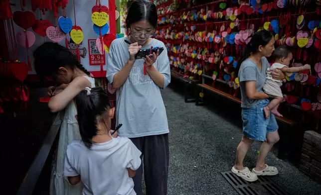 2026年8月29日周六，一名女子與兒童在中國南方廣東省珠海的歷史文化景點北山大院許願巷寫下願望卡。(美聯社圖片/Andy Wong) AP圖片