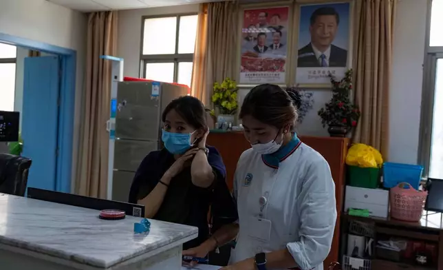 2026年7月22日周三，外國記者在政府組織的行程中，於中國西部西藏自治區拉薩的西藏自治區藏醫院內，護士在中國國家主席習近平的肖像旁工作。 (美聯社圖片/Ng Han Guan) AP圖片