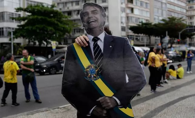 反對派總統候選人弗拉維奧·博爾索納羅的支持者，周日（2026年8月16日）抵達巴西里約熱內盧出席競選集會，手持弗拉維奧·博爾索納羅的父親、前總統博爾索納羅的肖像。（美聯社圖片/Bruna Prado） AP圖片