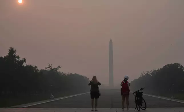 (美聯社圖片/Julia Demaree Nikhinson) 檔案圖片：2026年7月17日，華盛頓國家廣場，太陽被山火濃煙遮蔽，人們駐足拍攝華盛頓紀念碑及林肯紀念堂倒影池。 AP圖片