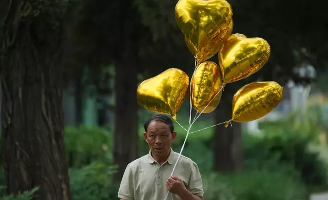 一名男子周二（2026年8月11日）在北京行人路上手持氣球行走。(美聯社圖片/Achmad Ibrahim) AP圖片