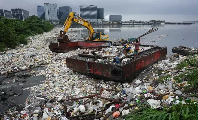 2026年8月12日周三，菲律賓馬尼拉大都會帕賽市，工人搬運竹子，旁邊是因強烈季候雨沖上岸的垃圾海。(美聯社圖片/Aaron Favila) AP圖片
