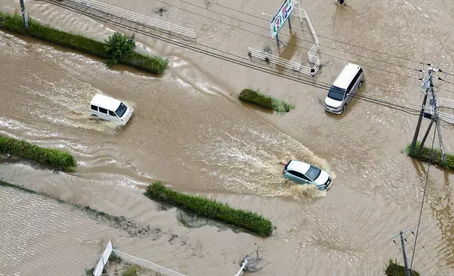 2026年8月14日周五，日本千葉縣大網白里市，汽車在暴雨過後被洪水淹浸的道路上行駛。(Kota Endo/共同社圖片/美聯社) AP圖片
