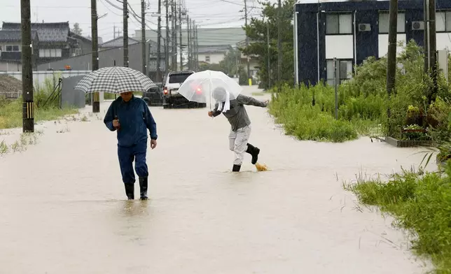 周四（2026年8月27日），日本石川縣羽咋市，民眾走過因暴雨而水浸的街道。(美聯社圖片/Yusuke Ogata/共同社) AP圖片