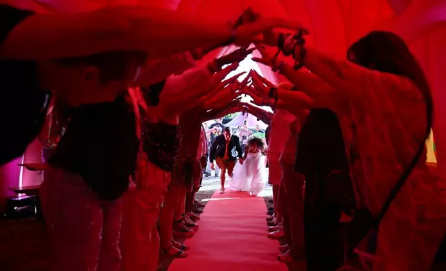 2026年8月6日周四，荷蘭阿姆斯特丹舉行一場集體婚禮，賓客為一對新人搭建人肉拱門，讓他們進入充氣教堂。這次活動是同志驕傲活動一部分，慶祝荷蘭成為全球首個將同性婚姻合法化的國家25周年。(美聯社圖片/Mouneb Taim) AP圖片