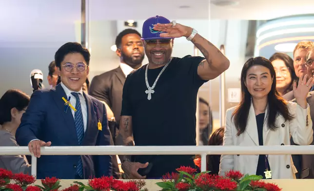 NBA傳奇球星艾佛遜（中）在跑馬地馬場廂房露台與馬會董事霍啟剛（左）及其妻子郭晶晶（右）向馬迷揮手致意。