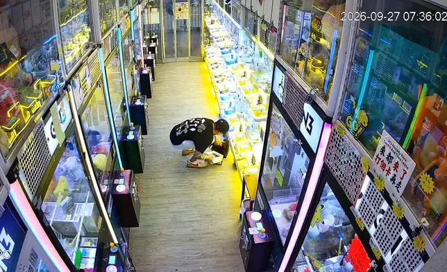 賊人把公仔機錢箱內硬幣倒進環保袋。閉路電視畫面截圖