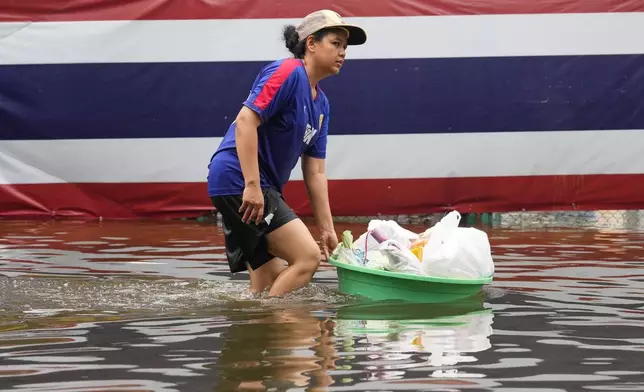 2026年9月27日周日，泰國曼谷一名女子在暴雨過後，於國旗前涉水而行。(美聯社圖片/Sakchai Lalit) AP圖片
