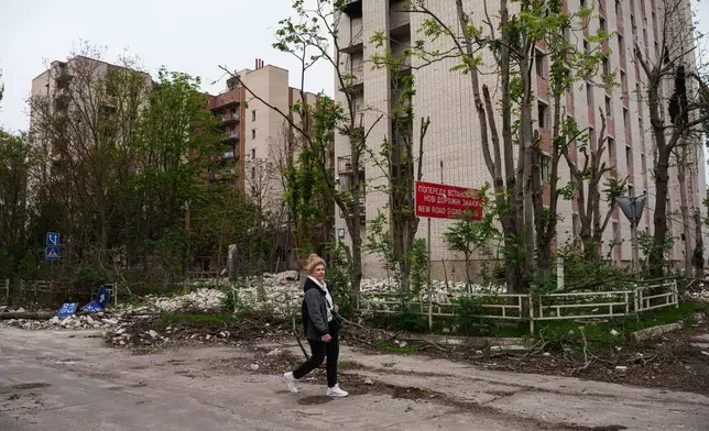 一名當地女子周三（2026年10月28日）在烏克蘭赫爾松市，奧列什基人道援助任務相關的局部停火期間，走過一棟在俄羅斯襲擊中受損的住宅大樓前。(美聯社圖片/Evgeniy Maloletka) AP圖片