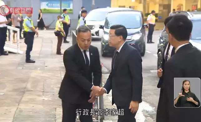 高級警員朱振國在紅磡世界殯儀館設靈，行政長官李家超(右)到場致意，左為警務處處長周一鳴。有線新聞視頻截圖