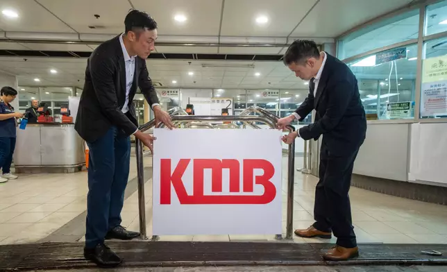 九巴車務總監楊晉瑋（右）和傳訊及公共事務部主管簡學悕（左）將九巴標誌貼於皇巴士告示上。