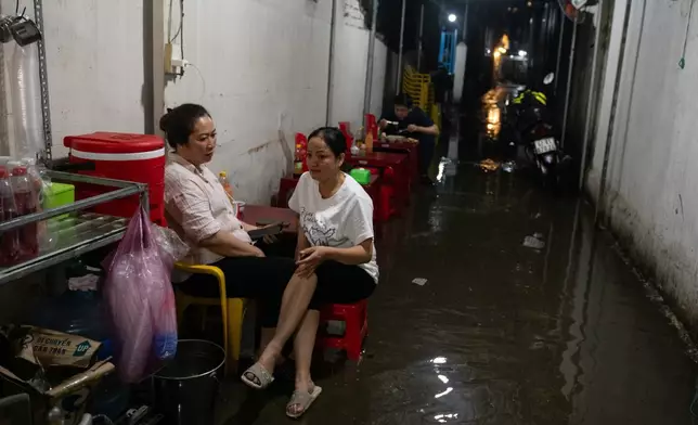 人們坐在越南胡志明市Pham Huu Lau街一間被水浸的巷弄食店旁，攝於2026年9月30日周三。(美聯社圖片/Thanh Hue) AP圖片