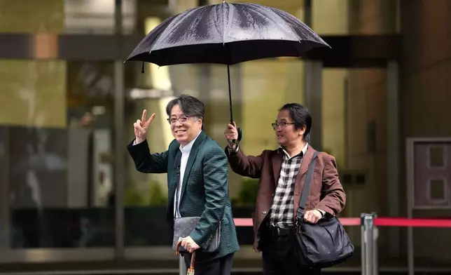 日本漫畫家小林善範（左），同時是歷史及君主制書籍作者，於2026年10月26日周一抵達東京的東京地方法院時做出手勢。(美聯社圖片/Eugene Hoshiko) AP圖片