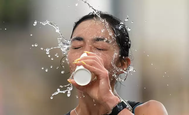 哈薩克選手托克桑巴耶娃在日本名古屋舉行的亞洲運動會女子馬拉松競走比賽中，向臉上潑水。攝於2026年9月27日周日。(美聯社圖片/Lee Jin-man) AP圖片