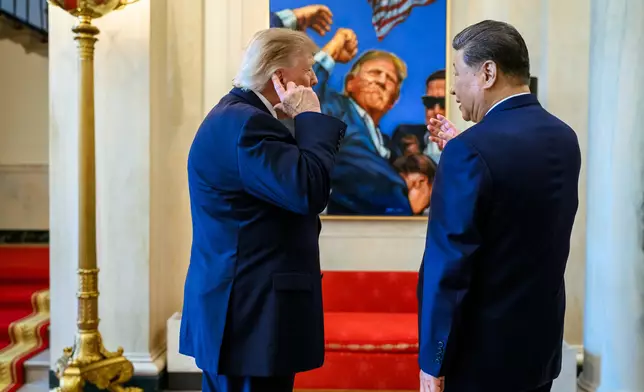 特朗普在一幅描繪自己2024年競選期間遭遇暗殺未遂後舉起拳頭的畫作前，與習近平交談，其間以右手指向被子彈擦過受傷流血的右耳位置