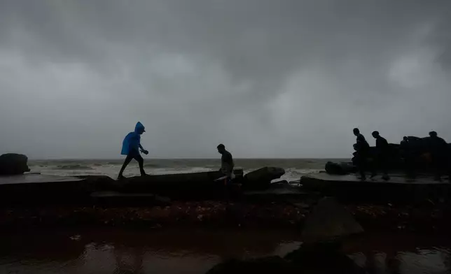 2026年10月28日周三，印度卡基納達烏帕達，氣旋阿爾納布當日稍早吹襲安得拉邦海岸後，民眾在岸邊一條受損道路上行走。(美聯社圖片/Mahesh Kumar A.) AP圖片