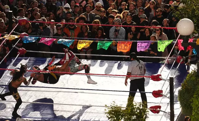 周五（2026年10月23日），Lucha Libre Volcánica摔角手在西雅圖派克市場的亡靈節慶祝活動期間，向大批觀眾表演。(美聯社圖片/Lindsey Wasson) AP圖片