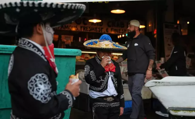 周五（2026年10月23日），墨西哥青年民間舞蹈團體Santana Charro Bros.的Thomas Santana在西雅圖派克市場的亡靈節慶祝活動表演間隙吃零食。(美聯社圖片/Lindsey Wasson) AP圖片