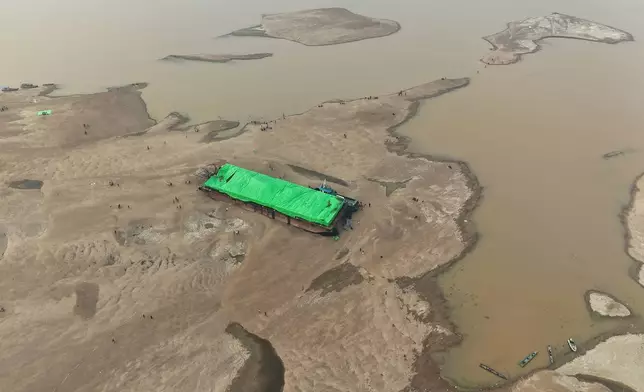 人們圍繞著一艘在印尼西加里曼丹西卡道，卡普阿斯河乾旱河床上擱淺的駁船。攝於2026年9月11日周五。(美聯社圖片/Tatan Syuflana) AP圖片