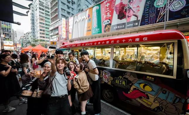 市民與旅客於特別打造的港式紅VAN「旺角妖巴」前自拍打卡