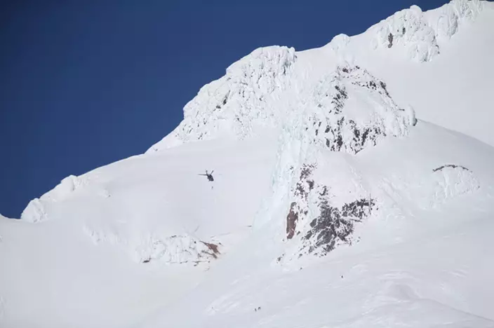 A rescue helicopter and ground teams attempt to reach stranded climbers on Mount Hood in Oregon on Tuesday, Feb. 13, 2018. Rescuers scrambled up Oregon's tallest peak Tuesday after a climber fell several hundred feet and several others were stranded, authorities said. (Dave Killen/The Oregonian via AP)