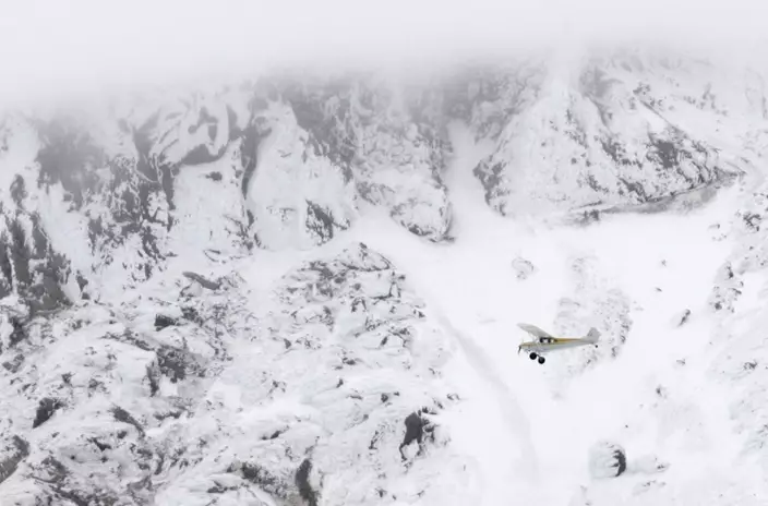 In this Dec. 20, 2006, file photo, a piper cub airplane with Hood River County officials in it flies past the steep, rocky slopes of Mount Hood, Ore., in search of two missing climbers. (AP Photo/Don Ryan, File)