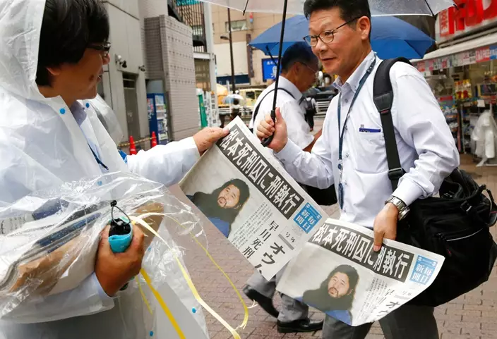 A staff of Japanese newspaper Mainichi Shimbun distributes their extra edition reporting that doomsday cult leader Shoko Asahara was executed, in Tokyo Friday, July 6, 2018. Asahara and six followers were executed Friday for their roles in a deadly 1995 gas attack on the Tokyo subways and other crimes, Japan's Justice Ministry said. (AP Photo/Shuji Kajiyama)