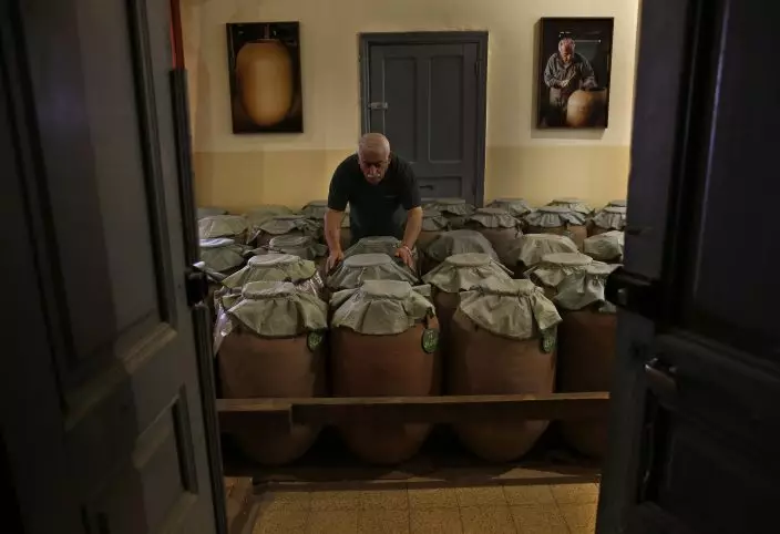 In this Saturday Sept. 8, 2018 photo, a worker checks clay jugs of arak, Lebanon's national alcoholic drink, at the Doumaine de Tourelles winery, in the town of Chtaura, east Lebanon. Homemade arak usually goes straight into gallon containers after distillation, ready for drinking. In commercial production, the arak sits in clay jugs for a year, making it smoother. (AP PhotoHussein Malla)