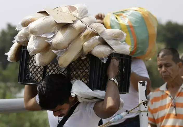A Venezuelan man carries a crate filled with bread back to his country, in La Parada, on the outskirts of Cucuta, Colombia, on the border with Venezuela, Monday, Feb. 4, 2019. More than a dozen European Union countries endorsed Venezuelan opposition leader Juan Guaido as the county's interim president on Monday, piling the pressure on embattled President Nicolas Maduro to resign and clear the way for a new presidential election. (AP PhotoFernando Vergara)