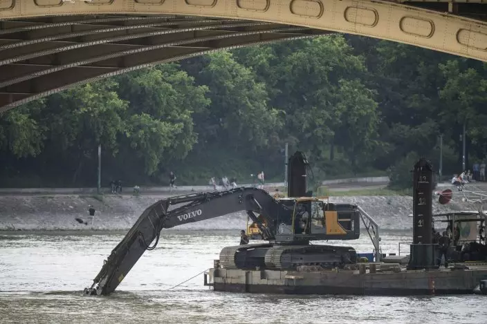 A power shovel fixed onto a pontoon works in Danube river near Margaret Bridge, the scene of a boat accident, in Budapest, Hungary, Thursday, June 6, 2019. Search operations continue after a sightseeing boat carrying 33 South Korean tourists was crashed into by a large river cruise ship and sank on May 29, killing at least fifteen tourists. (Marton MonusMTI via AP)