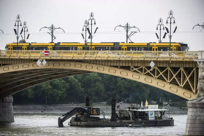 A power shovel fixed onto a pontoon works in Danube river near Margaret Bridge, the scene of a boat accident, in Budapest, Hungary, Thursday, June 6, 2019. Search operations continue after a sightseeing boat carrying 33 South Korean tourists was crashed into by a large river cruise ship and sank on May 29, killing at least fifteen tourists. (Marton MonusMTI via AP)