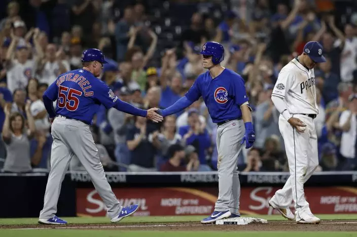 Chicago Cubs' Nico Hoerner, center, is greeted by third base coach Brian Butterfield (55) after hitting a triple as San Diego Padres third baseman Manny Machado looks on, right, during the fifth inning of a baseball game Monday, Sept. 9, 2019, in San Diego. (AP PhotoGregory Bull)