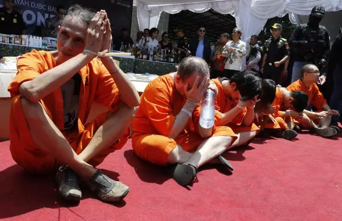 Foreign suspects detained for drugs charges sit during a press conference in Bali, Indonesia, Wednesday, Dec. 18, 2019. Indonesian authorities say they have arrested six foreigners for allegedly trying to smuggle drugs onto the tourist island of Bali. The foreigners, a Swiss man, a Thai man, a Singaporean woman, a Chilean man and two Hong Kong men, wearing orange detainees uniform were paraded with their feet and hands tied, at a news conference. (AP PhotoFirdia Lisnawati)