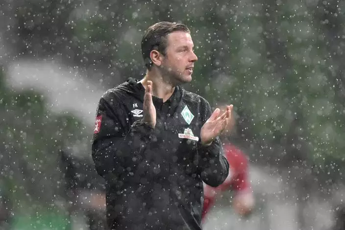 Bremen's head coach Florian Kohfeldt encourages his team under heavy rain during the German Bundesliga soccer match between Werder Bremen and Bayern Munich in Bremen, Germany, Tuesday, June 16, 2020. Because of the coronavirus outbreak all soccer matches of the German Bundesliga take place without spectators. (AP PhotoMartin Meissner, Pool)