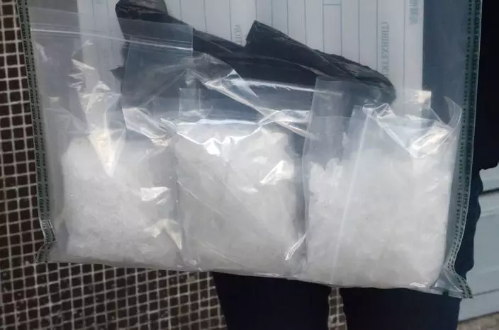 海關人員展示從少年斜孭袋搜獲的懷疑冰毒 。