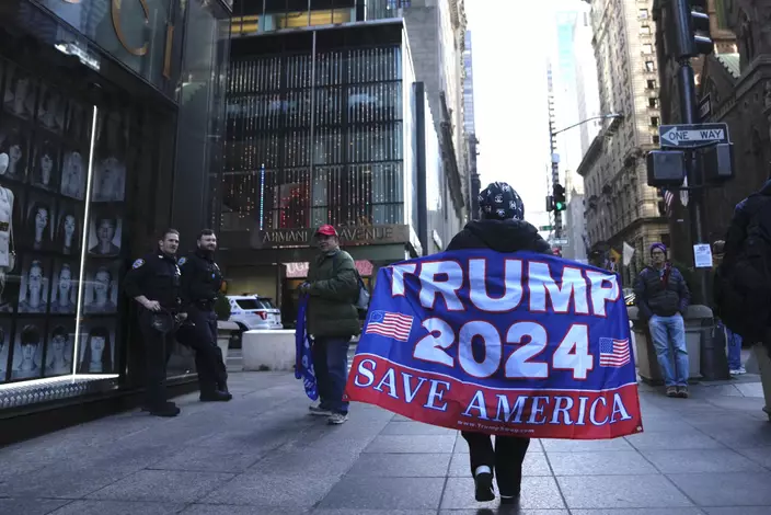 一名婦女在第五大道上行走，舉著一面支持前總統特朗普的旗幟。AP圖片